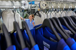 A worker arranges the business suits at Shandong Daiyin Textile and Garment Group factory in Tai'an in east China's Shandong province on Saturday, May 29, 2021. China's manufacturing held steady in May, a survey showed Monday, adding to signs a post-pandemic rebound is leveling off.