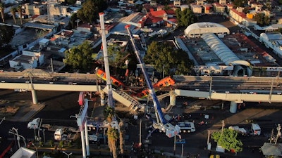 In this May 4, 2021 file photo, subway cars dangle at an angle from a collapsed elevated section of the metro in Mexico City, the day after the collapse. A preliminary report on June 16, 2021, by experts into the collapse that killed 26 people placed much of the blame on poor welds in studs that joined steel support beams to a concrete layer supporting the trackbed.