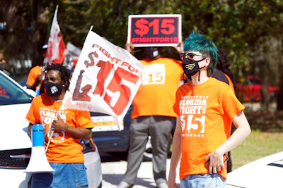 Cristian Cardona, right, an employee at a McDonald's, attends a rally for a $15 an hour minimum wage on Feb. 16 in Orlando, FL.