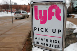 In this Wednesday, Feb. 12, 2020, photo, a sign marks the pick lane for Lyft car share service outside the Pepsi Center in downtown Denver. Ford Motor Co. and a self-driving vehicle company it partly owns will join with the Lyft ride-hailing service to offer autonomous rides on the Lyft network. The service using Ford vehicles and a driving system developed by Argo AI will begin in Miami later this year and start in Austin, Texas, in 2022.