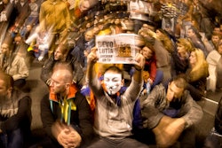FILE - In this Sunday, Oct. 20, 2013 file photo, protesters, one wearing a mask and holding a poster that reads 'The revolution starts from Rosia Montana,' sit on the pavement, blocking the traffic, in front of the Romanian parliament during a protest against a Canadian gold mining project in Bucharest, Romania. Rosia Montana, the site of ancient Roman mining galleries in a mountainous western Romanian region and home to Europe's largest gold deposits, an estimated 314 tonnes, which was set to be exploited over a 16-year period by Gabriel Resources, a Canadian mining company that gained concession rights to the area in 1999, was added to UNESCO's World Heritage list Tuesday, July 27, 2021.