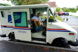U.S. Postal Service carrier John Graham packs his mail bag after parking a 28-year-old delivery truck, Wednesday, July 14, 2021, in Portland, Maine. The Postal Service’s aging fleet of trucks is soldiering on even as a contract for greener replacement vehicles is being challenged. The primary fleet of vehicles that were delivered starting in 1987 is due to be replaced under a new contract, but the winning bid is being challenged.