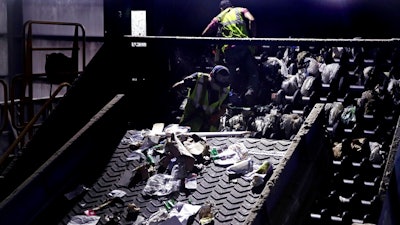 In this Thursday, Sept. 6, 2018, file photo, workers clean consumer plastic shopping bags from the clogged rollers of a machine which separates paper, plastic and metal recyclable material, in a processing building at EL Harvey & Sons, a waste and recycling company, in Westborough, Mass. States around the country are looking to adopt new recycling regimes that require producers of packaging to pay for its inevitable disposal.