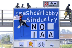 An activist hangs from a gantry over the A9 motorway near Fürholzen in the direction of Munich during a banner campaign, holding a banner with the words 'Destroy cars' in his hands while police officers from a special task force get into position on the gantry, Tuesday, Sept.7, 2021. The activists have pasted over the traffic sign with the words 'smashcarlobby & industry - NO IAA.'