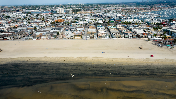 Workers in protective suits clean a contaminated beach in Newport Beach, Calif., Oct.6, 2021.