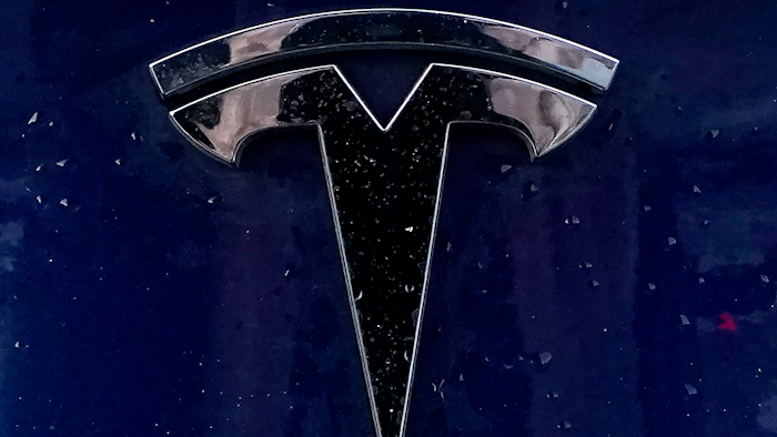 A Tesla electric vehicle emblem is affixed to a passenger vehicle Sunday, Feb. 21, 2021, in Boston. U.S. highway safety investigators want to know why Tesla didn’t file recall paperwork when it updated Autopilot software so it would do a better job spotting parked emergency vehicles.