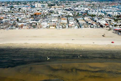 In this Wednesday, Oct.6, 2021 aerial image taken with a drone, workers in protective suits clean the contaminated beach after an oil spill in Newport Beach, Calif. California's uneasy relationship with the oil industry is being tested again by the latest spill to foul beaches and kill birds and fish off Orange County.