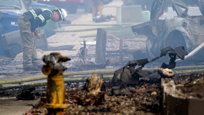A fire official looks over the scene of a small plane crash, Monday, Oct. 11, 2021, in Santee, Calif. At least two people were killed and two others were injured when the plane crashed into a suburban Southern California neighborhood, setting two homes ablaze, authorities said.