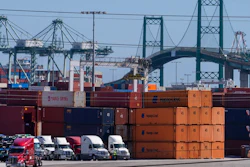 In this Tuesday, Oct. 19, 2021, photo trucks line up next to containers at the Port of Los Angeles in san Pedro, Calif. The Vincent Thomas Bridge suspension bridge, crossing the Los Angeles Harbor links San Pedro with Terminal Island. California Gov. Gavin Newsom on Wednesday, Oct. 20, 2021 issued an order that aims to ease bottlenecks at the ports of Los Angeles and Long Beach that have spilled over into neighborhoods where cargo trucks are clogging residential streets. Last week the White House allowed the ports complex to become a 24-hour operation in an effort to break the logjam and reduce shipping delays.