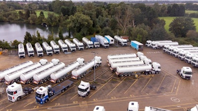 Trucks are parked as part of government's reserve tanker fleet based at a depot in Fenstanton, England, Saturday, Oct. 2, 2021. Military drivers will be deployed to deliver fuel to forecourts from Monday as the crisis at the pumps continues. The British government has extended an emergency visa program for truck drivers as fuel shortages frustrate motorists lining up at empty pumps.