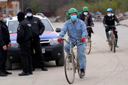 Vietnamese workers who are helping construct the first Chinese car tire factory in Europe ride bicycles past security officers near the northern Serbian town of Zrenjanin, 50 kilometers north of Belgrade, Serbia, Thursday, Nov. 18, 2021.