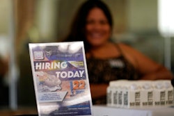 A hiring sign is placed at a booth for prospective employers during a job fair Wednesday, Sept. 22, 2021, in the West Hollywood section of Los Angeles. Workers seeking a new career may face challenges if they’re looking to retrain, labor experts say. That’s because there are few social supports in place that allow career-change aspirants the time and financial help to do it.