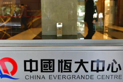 In this Oct. 4, 2021, file photo, a security guard stands at the headquarters of China Evergrande Group in Hong Kong. On Friday, Dec. 3, 2021, troubled Chinese developer China Evergrande Group, struggling under $310 billion in debt, warned it may run out of money to “perform its financial obligations,” sending regulators scrambling to reassure investors that China’s financial markets can be protected from a potential impact.