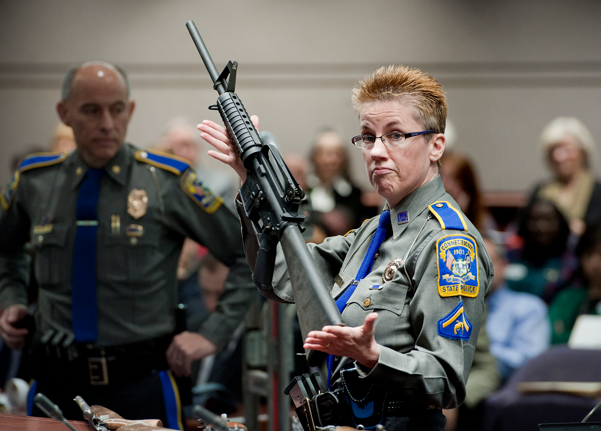 Firearms training unit Detective Barbara J. Mattson, of the Connecticut State Police, holds up a Bushmaster AR-15 rifle, the same make and model of gun used by Adam Lanza in the December 2012 Sandy Hook School shooting, during a hearing of a legislative subcommittee in Hartford, Conn., Jan. 28, 2013.