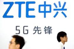 Visitors walk past a display from Chinese technology firm ZTE at the PT Expo in Beijing, Sept. 26, 2018. ZTE Corp. said Wednesday, March 23, 2022, a U.S. judge has allowed a probation period to end after the telecom equipment maker was nearly destroyed in a clash with Washington over its dealings with Iran and North Korea.