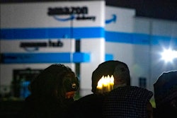 A person holds six electric candles symbolizing the six workers who died while working at the Edwardsville Amazon site in the background, during a vigil, Friday, Dec. 17, 2021, in Edwardsville, Ill., after part of the building collapsed due to a tornado the previous week before. Democratic members of the House Committee on Oversight and Reform are accusing Amazon of “obstructing” their investigation into the company's labor practices during severe weather events. Amazon's policies have been under more scrutiny since the deadly collapse of a company warehouse last year in Edwardsville.