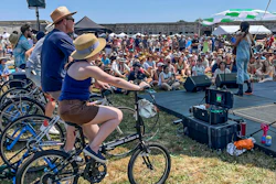 Madi Diaz, right, performs at the Newport Folk Festival's bike stage, powered in part by festivalgoers on stationary bicycles, left, Friday, July 22, 2022, in Newport, R.I.
