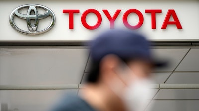 A man walks past a Toyota dealer in Tokyo on May 11, 2022. Toyota Motor Corp. reported Thursday, Aug. 4, 2022 a quarterly profit of 736.8 billion yen ($5.5 billion), down from 897.8 billion yen the previous year.