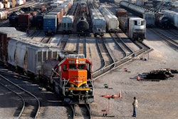 A BNSF rail terminal worker monitors the departure of a freight train, June 15, 2021, Galesburg, Ill.