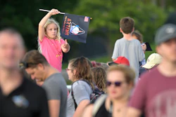 A child waves a souvenir flag while waiting on the Max Brewer Bridge to view the launch on Pad 39B for the Artemis I mission to orbit the moon at the Kennedy Space Center, Monday, Aug. 29, 2022, in Titusville, Fla. The launch was scrubbed.