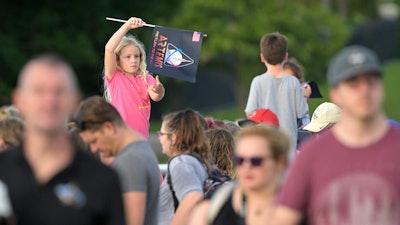 A child waves a souvenir flag while waiting on the Max Brewer Bridge to view the launch on Pad 39B for the Artemis I mission to orbit the moon at the Kennedy Space Center, Monday, Aug. 29, 2022, in Titusville, Fla. The launch was scrubbed.