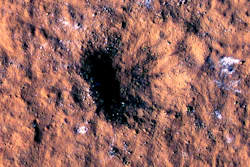 In this image made available by NASA on Thursday, Oct. 27, 2022, boulder-size blocks of water ice are seen around the rim of an impact crater on Mars, as viewed by the High-Resolution Imaging Science Experiment (HiRISE camera) aboard NASA's Mars Reconnaissance Orbiter. The crater was formed Dec. 24, 2021, by a meteoroid strike in the Amazonis Planitia region.