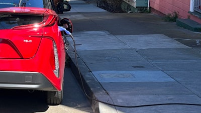 A charging cord for an electric vehicle is seen strung across a public sidewalk in San Francisco on Sept. 23, 2022.