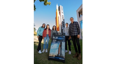 Student employees in the Industry Design Experience for Auburn Students, or IDEAS, program stand by a blow-up replica of the Space Launch System they are working on.