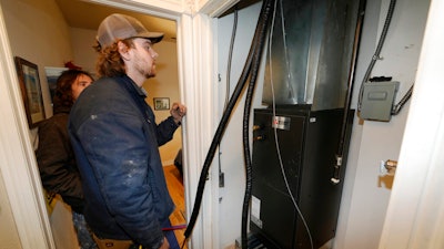 John Paul, front, and David Valenzuela work to install a heat pump in an 80-year-old rowhouse Friday, Jan. 20, 2023, in northwest Denver.