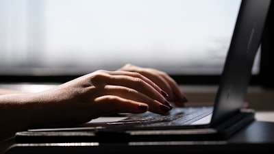 A woman types on a laptop while on a train in New Jersey, May 18, 2021.