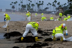 Workers in protective suits clean the contaminated beach in Corona Del Mar after an oil spill in Newport Beach, Calif., Oct. 7, 2021.