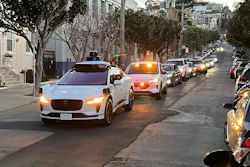A Waymo driverless taxi stops on a street in San Francisco for several minutes because the back door was not completely shut, while traffic backs up behind it, on Feb. 15, 2023.