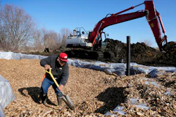 A worker shovels wood chips in a bioreactor trench in a farm field, Tuesday, March 28, 2023, near Roland, Iowa.