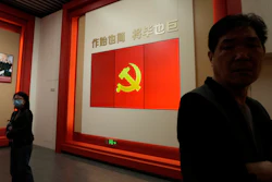 Visitors stand near a flag of the Chinese Communist Party at an exhibition in Shanghai, Thursday, April 20, 2023.