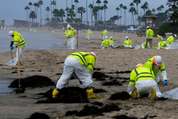 Workers in protective suits clean the contaminated beach in Corona Del Mar after an oil spill in Newport Beach, Calif., Oct. 7, 2021.