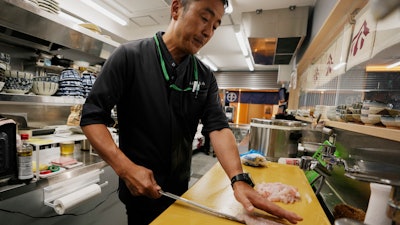 Katsumasa Okawa, owner of a fish store and a restaurant, cuts flounder meat, Iwaki, Japan, July 13, 2023.