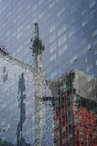 A glass paneled building reflects a hi-rise construction site crane, center, in the aftermath of a fire yesterday, that sent its extension arm plummeting to the street, Thursday July 27, 2023, in New York.