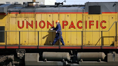 A maintenance worker walks on the side of a locomotive in the Union Pacific Railroad fueling yard, Denver, Oct. 18, 2006.