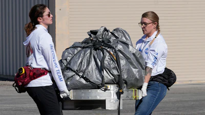 Recovery team members carry a capsule containing NASA's first asteroid samples to a temporary clean room at Dugway Proving Ground in Utah on Sunday, Sept. 24, 2023.