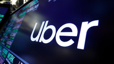 The logo for Uber appears above a trading post on the floor of the New York Stock Exchange, Aug. 16, 2019. The ride-hailing and delivery company said Wednesday, Oct. 4, 2023, that its drivers will collect up to five prepaid and sealed packages and drop them off at a local post office or at UPS or FedEx stores. Uber will charge a flat fee of $5 for the service or $3 for its Uber One members.
