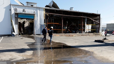 A Massachusetts Department of Environmental Protection worker walks in front of the damaged Seqens plant after crews removed chemicals, May 5, 2023, in Newburyport, Mass.
