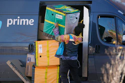 An Amazon Prime delivery person struggles with packages while making a stop at a high-rise apartment building on Tuesday, Nov. 28, 2023, in Denver.