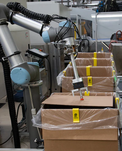 The molded parts arrive from the Cartesian robot via conveyor to the UR10 that picks them up and places them in boxes.