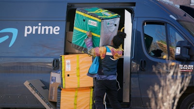 An Amazon Prime driver lifts packages during a stop at a Denver high-rise, Nov. 28, 2023.