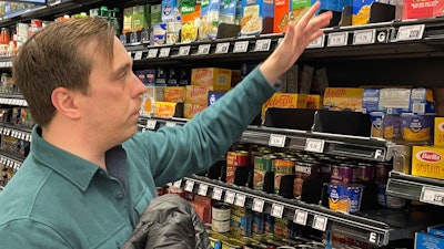 Stuart Dryden reaches for an item at a grocery store, Feb. 21, 2024, Arlington, Va.