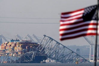 An American flag flies on a moored boat as the container ship Dali rests against wreckage of the Francis Scott Key Bridge, Tuesday, March 26, 2024, as seen from Pasadena, Md.