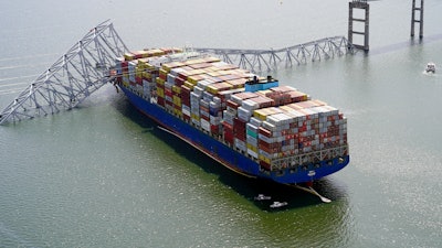In this aerial image released by the Maryland National Guard, the cargo ship Dali is stuck under part of the structure of the Francis Scott Key Bridge after the ship hit the bridge, Tuesday, March 26, 2024, in Baltimore.