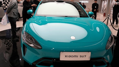 Visitors to the Xiaomi Automobile flagship store look at the Xiaomi SU7 electric car on display in Beijing, Tuesday, March 26, 2024.