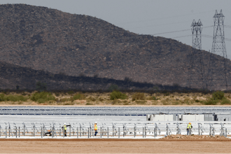 Workers continue to build rows of solar panels at a Mesquite Solar 1 facility under construction in Arlington, Ariz.