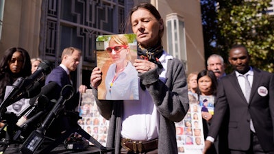 Catherine Berthet, of France, closes her eyes as she holds a photo of her deceased daughter Camille Geoffroy, in front of other families that lost loved ones to crashes of the Boeing 737 Max airliner outside the federal court in Fort Worth, Texas, Thursday, Jan. 26, 2023.